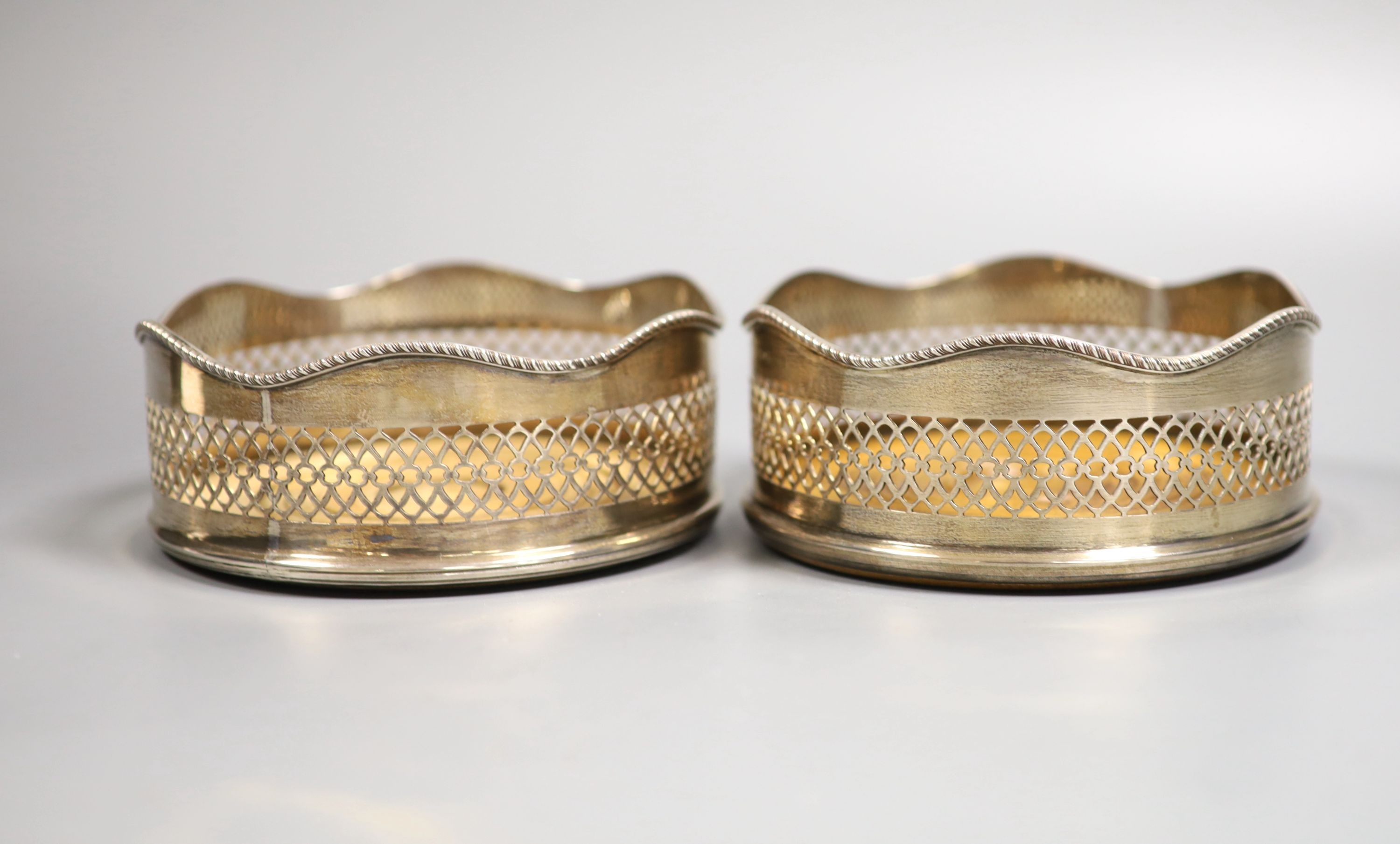 A pair of modern silver wine coasters, with wavy rims and fretwork sides, Birmingham, 1974/5, diameter 13.5cm.